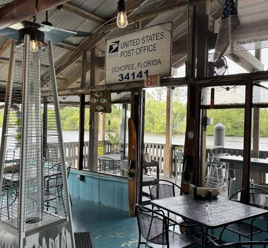 Screened dining room with an old Ochopee post office sign, river outside