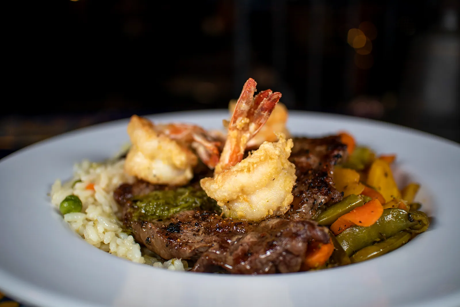 Steak topped with shrimp and grilled vegetables